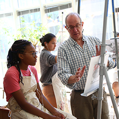An art teacher helping a student. Links to Beneficiary Designations